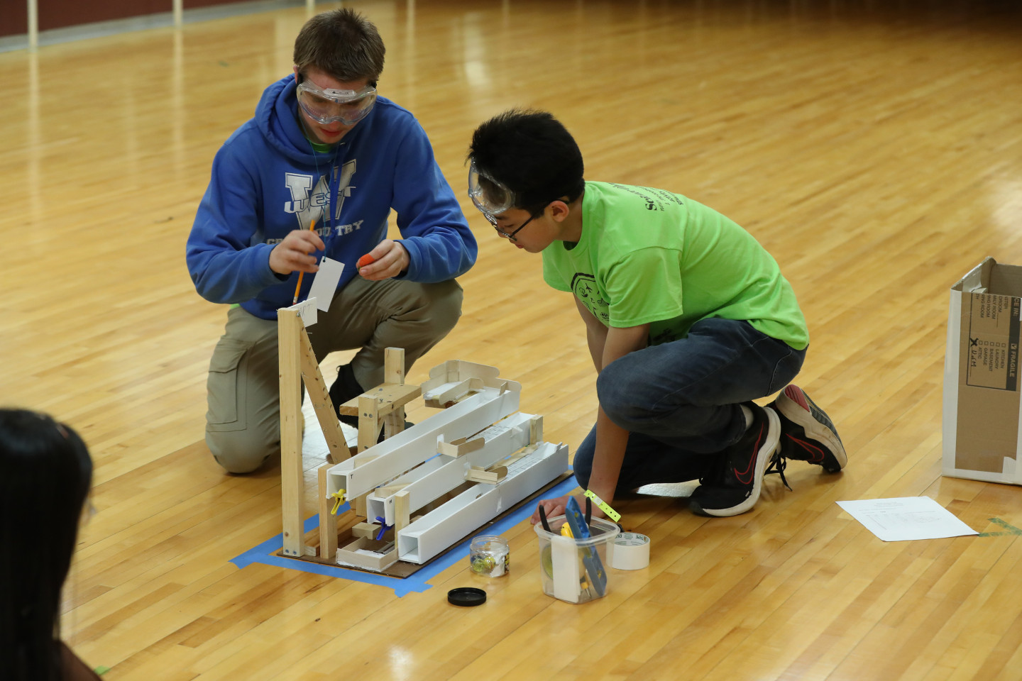 A ܽƵ student assists a participant in the Regional Science Olympiad event held at ܽƵ.